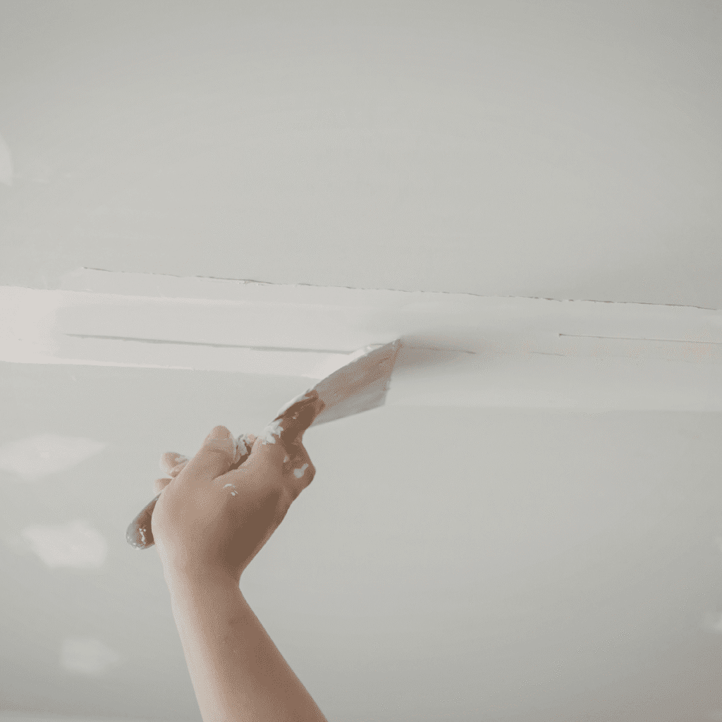 Wall damage being repaired with drywall patching compound