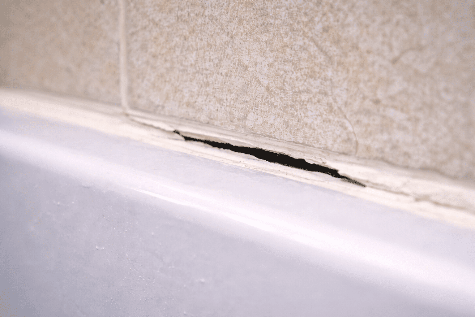worn silicone caulking around bathtub in Toronto bathroom showing need for professional recaulk service