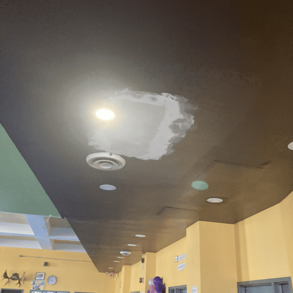 Ceiling surface being sanded to create a smooth base before plastering