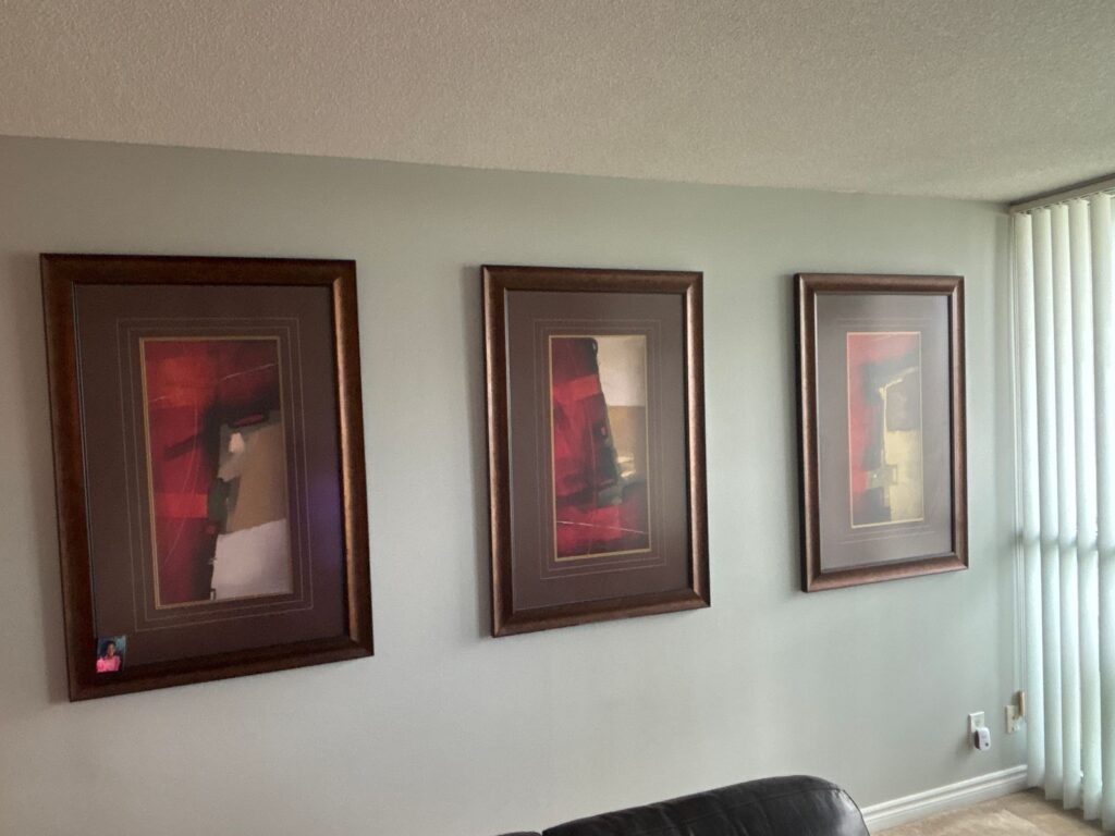 Three framed pictures hung level and evenly spaced on a living room wall