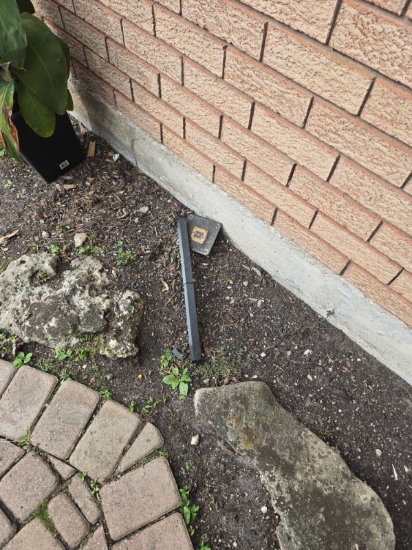 Loose outdoor lighting wire and stake beside a brick wall in a Thornhill garden bed