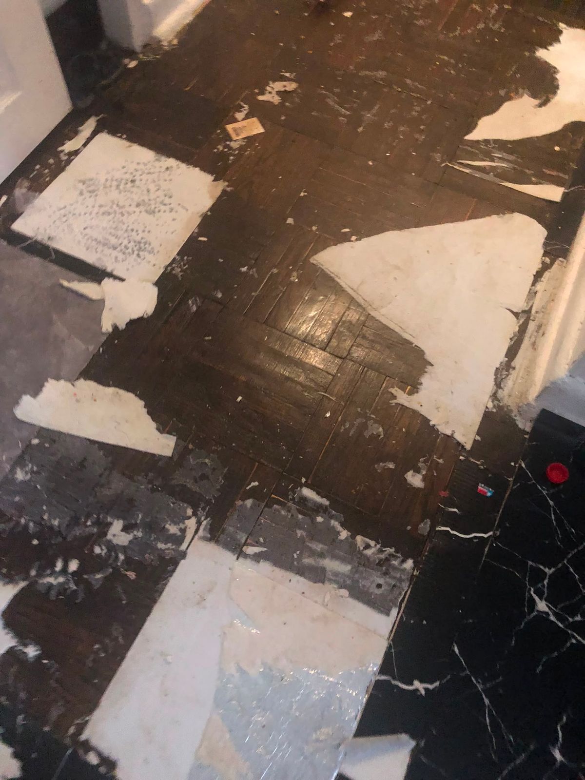 Black peel and stick tiles partially removed from a subfloor