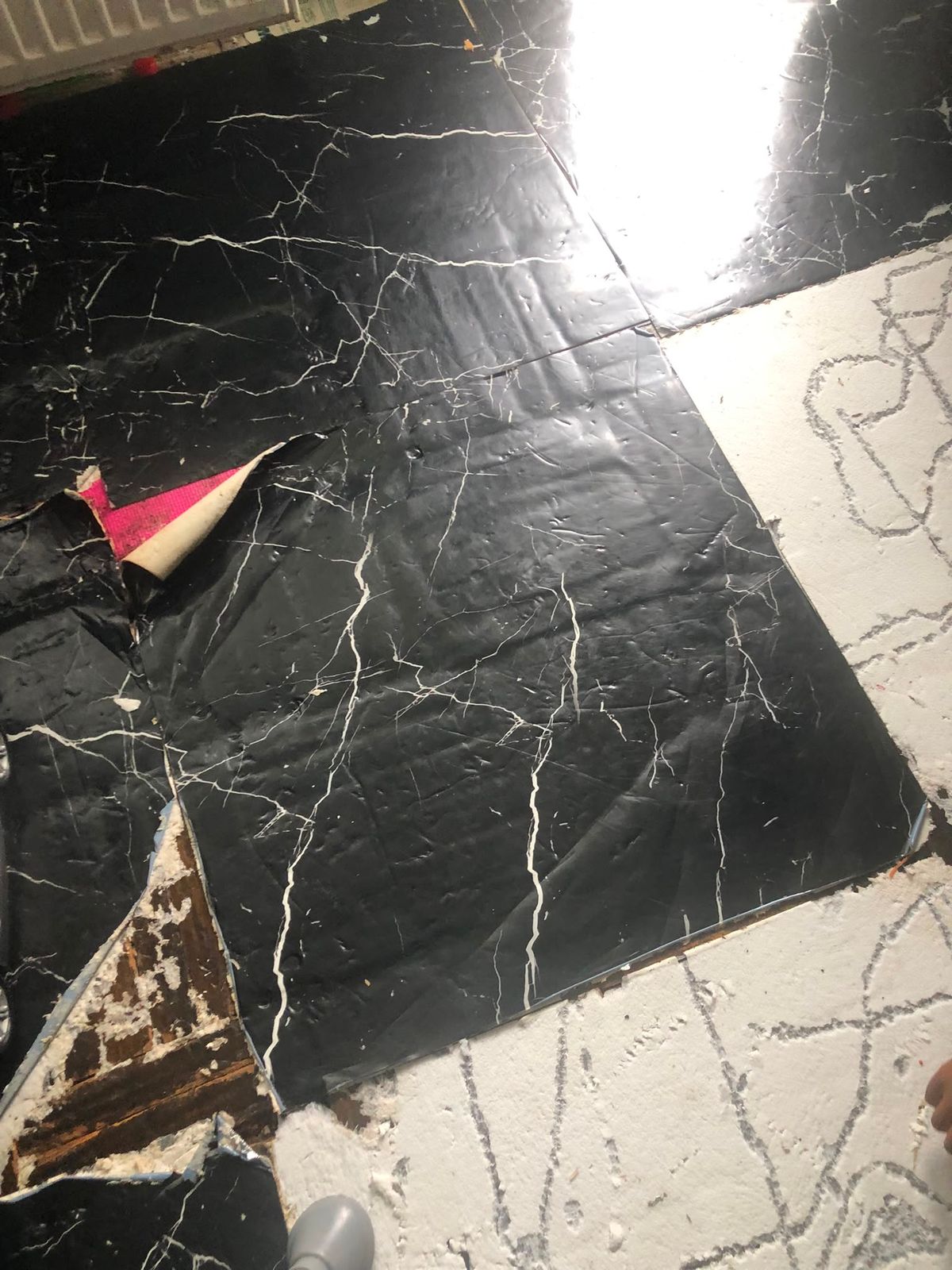Peel and stick flooring being lifted tile by tile