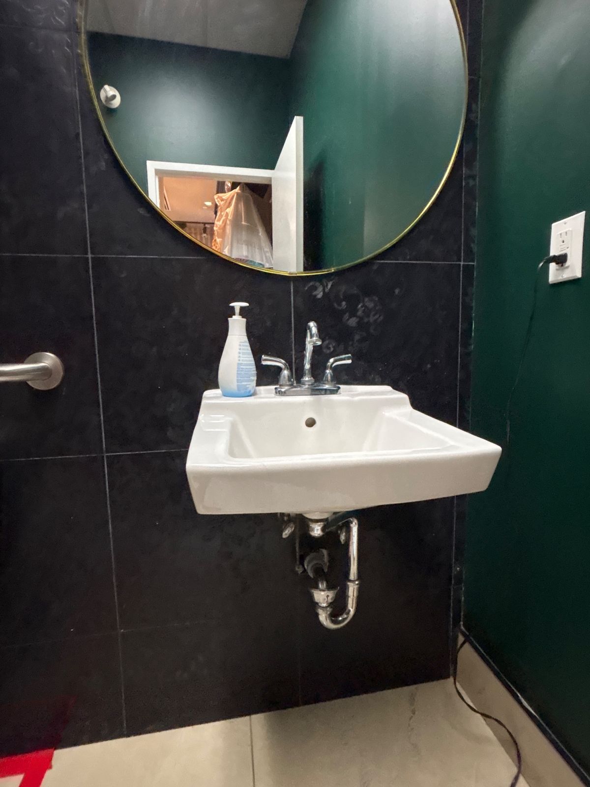 Wall-mounted bathroom sink and faucet installed in a dark green Brampton bathroom